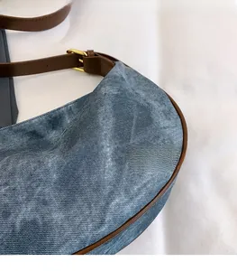 Detail of blue denim fabric with dark brown leather strap and golden metal buckle