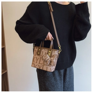 Detail einer Vintage-Einkaufstasche mit Lucky-Prints, Bärenanhänger und goldenen Beschlägen