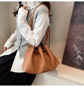 Detail of caramel brown drawstring bucket bag with pleated texture and knotted strap design