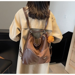 Close-up of vintage brown leather tote bag detail with plush teddy bear charm accessory