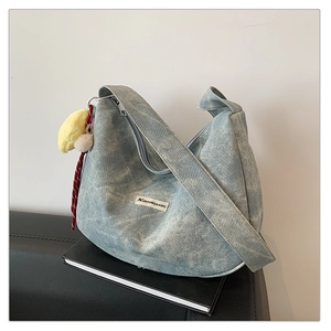 Detail view of light blue canvas hobo bag with a yellow sunflower plush charm accessory
