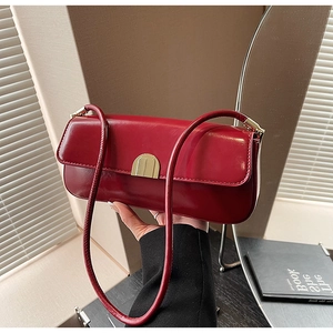 Detail of red rectangular underarm bag with a glossy finish and a golden metal clasp