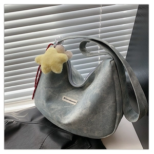 Detail of light blue denim hobo bag with grid texture and yellow plush star charm
