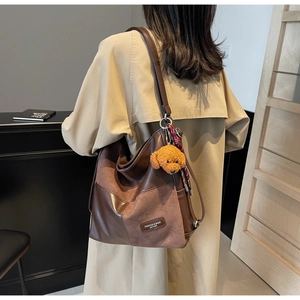 Detail of coffee brown patchwork tote bag with suede texture and plush puppy charm