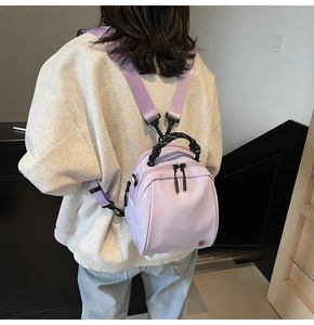 Rear view of a model wearing a mini purple shell backpack with woven top handle