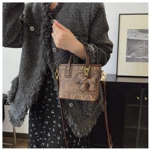 Detail der braunen Vintage-Tasche mit Kleeblattmustern und hundeförmigem Anhänger