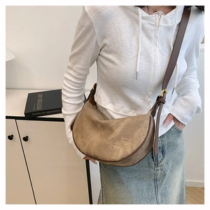 Brown faux suede crescent bag detail on model showing adjustable strap and texture