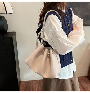 Detail of beige cloud bucket bag featuring lychee texture and unique knotted handle detail