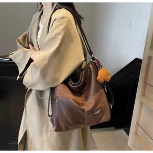Detail of vintage brown leather tote bag with patchwork suede and teddy bear charm