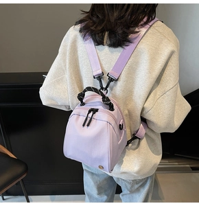 Light purple mini nylon backpack with woven handles worn by a model in a casual setting