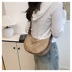 Detail view of khaki suede crescent bag with dark brown leather trim on female model