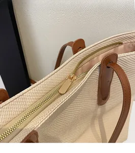 Detail of a smooth golden metal zipper and beige fabric on a large tote bag