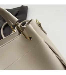 Gros plan des coutures précises et détails métalliques dorés sur sac crème