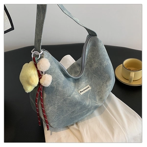 Detailed close-up of blue textured hobo bag with a yellow star and pom-pom keychain accessory