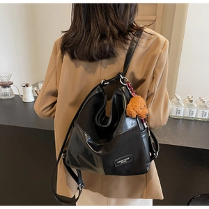 Detail of black tote bag with leather patchwork and cute plush dog charm accessory