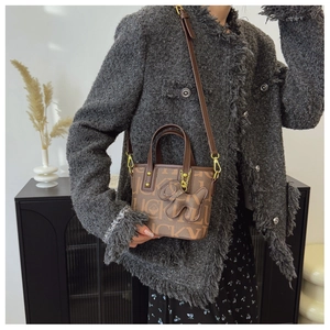 Nahaufnahme braune Leder-Tote-Bag mit Lucky-Print und kreativem Hunde-Anhänger