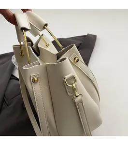 Détail d'un sac à main blanc crème avec poignée anneau doré et finitions rivets