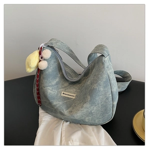 Close-up of textured blue hobo bag showing silver zipper and plush duck charm