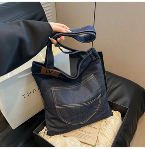 Detailed shot of a denim tote bag with leather trim inside a premium gift box set