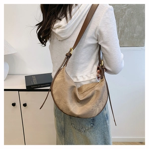 Detailed view of a khaki crossbody crescent bag with adjustable dark brown leather strap