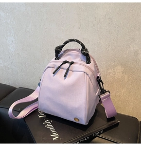Detail view of lavender canvas mini backpack with woven rope handle and dual zipper pockets