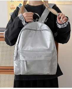 Detailed view of silver grey backpack with subtle leaf patterns and white embroidery