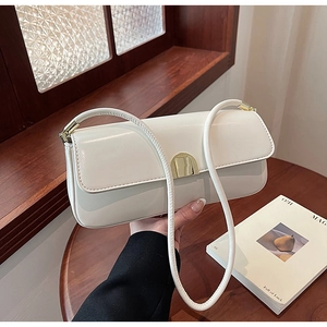 Detail of minimalist beige underarm bag with polished metal buckle on wooden table
