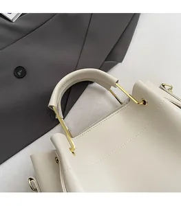 Détail du sac beige avec ferrures dorées en U et surpiqûres de haute qualité
