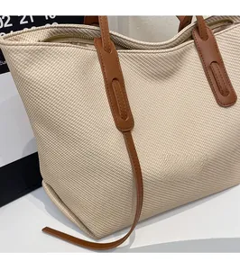 Close-up of beige twill weave tote bag with brown leather handle and zipper detail