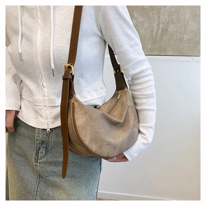 Detail of taupe hobo bag with brown leather trim and adjustable gold buckle strap