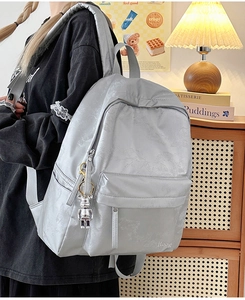 Detail of silver grey backpack with floral pattern, bear pendant and Hoog embroidery