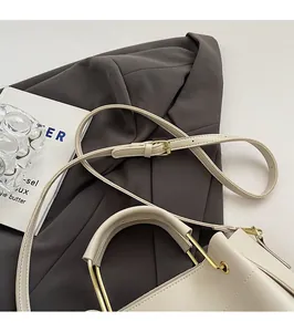 Détail du sac à main minimaliste en cuir beige avec bandoulière et ferrures dorées