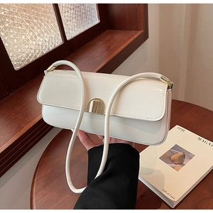 Detailed close-up of white leather baguette bag with minimalist gold metal buckle closure