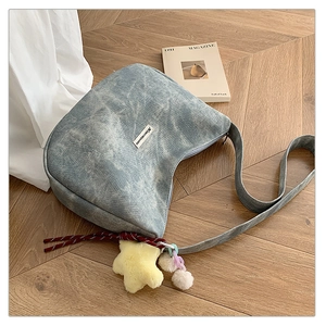 Close-up of blue denim hobo bag with star plush charm on a wooden background