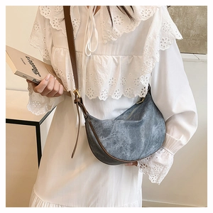 Detail of grey vintage canvas crescent bag with brown leather strap and metal buckle