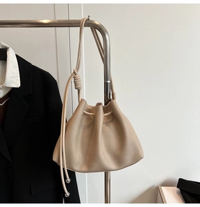 Close-up of beige lychee grain leather bucket bag with drawstring and silver metal tips