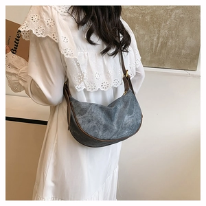 Detail of crescent shoulder bag featuring dark grey canvas and brown leather trim