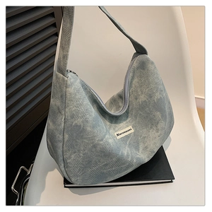 Close-up of washed denim texture and logo patch on this large half-moon hobo bag