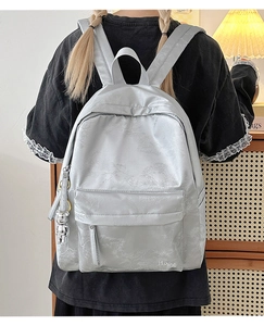 Detail of silver-grey floral jacquard backpack featuring Hoog embroidery and bear charm