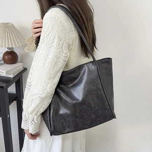 Detalle de un bolso tote grande gris oscuro con textura suave y diseño elegante minimalista