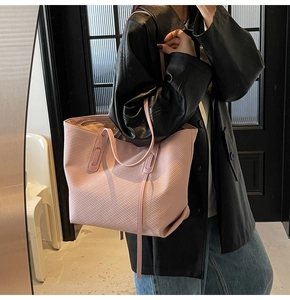 Pink tote bag detail with textured surface and slim straps on a model's shoulder