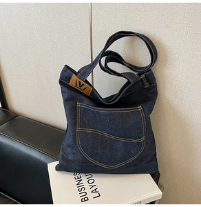 Detail of blue denim tote bag featuring yellow contrast stitching and leather brand logo