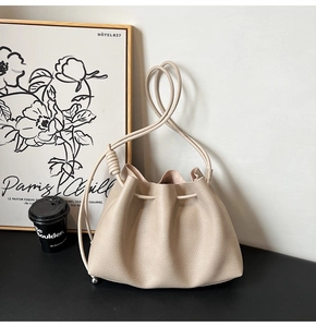 Close-up of beige drawstring bucket bag with lychee grain leather and silver hardware detail