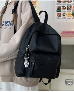 Close-up of black floral patterned nylon backpack featuring a silver bear keychain