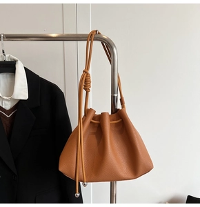 Detail of caramel bucket bag with pleated leather texture and silver ball drawstring