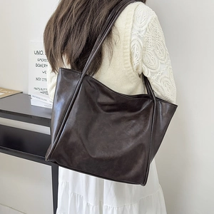 Detalle del bolso tote de cuero marrón vintage de gran capacidad llevado al hombro