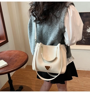 Vue détaillée du sac seau crème avec garniture métallique triangulaire et poignée supérieure