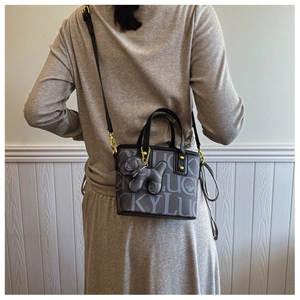 Detail der modischen Mini-Tasche mit LUCKY-Muster, Hundeanhänger und goldener Hardware