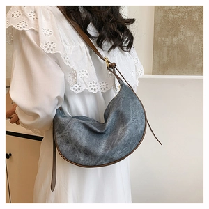 Detail of grey washed denim hobo bag with brown leather trim and adjustable strap