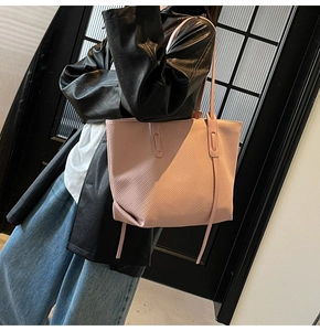 Detail showing the pink tote bag's unique diagonal texture and stylish decorative drawstrings